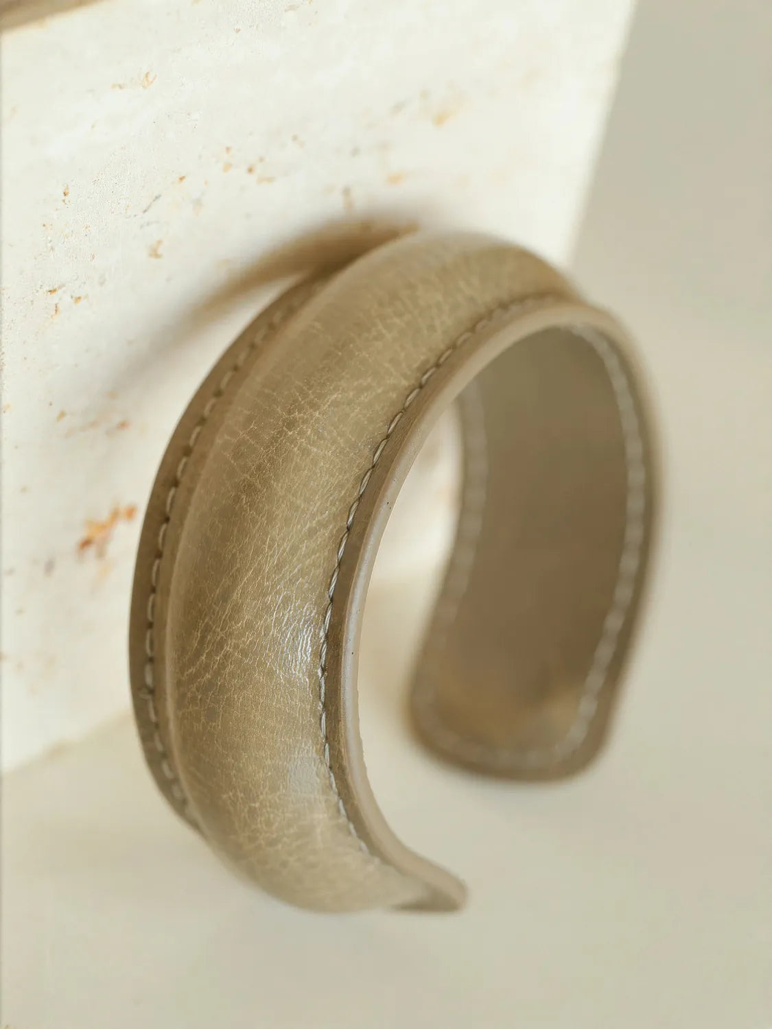 Beige leather ring on a textured beige surface